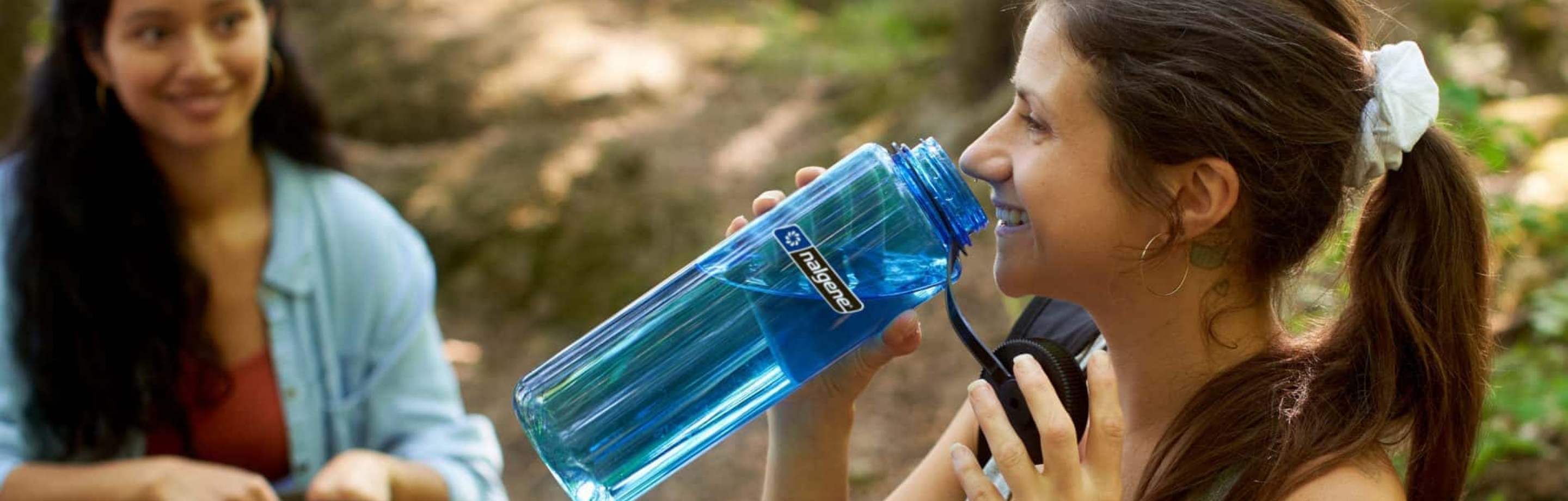 Dos chicas en el bosque con una botella de agua Nalgene de la marca 