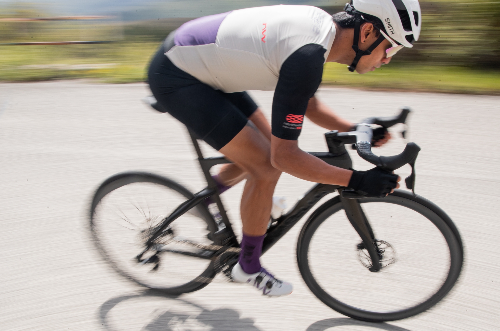 Northwave – Rennrad- & MTB-Schuhe, Brillen & Radbekleidung für Damen & Herren Rennradfahrer in Northwave-Outfit sprintet dynamisch auf asphaltierter Strecke.
