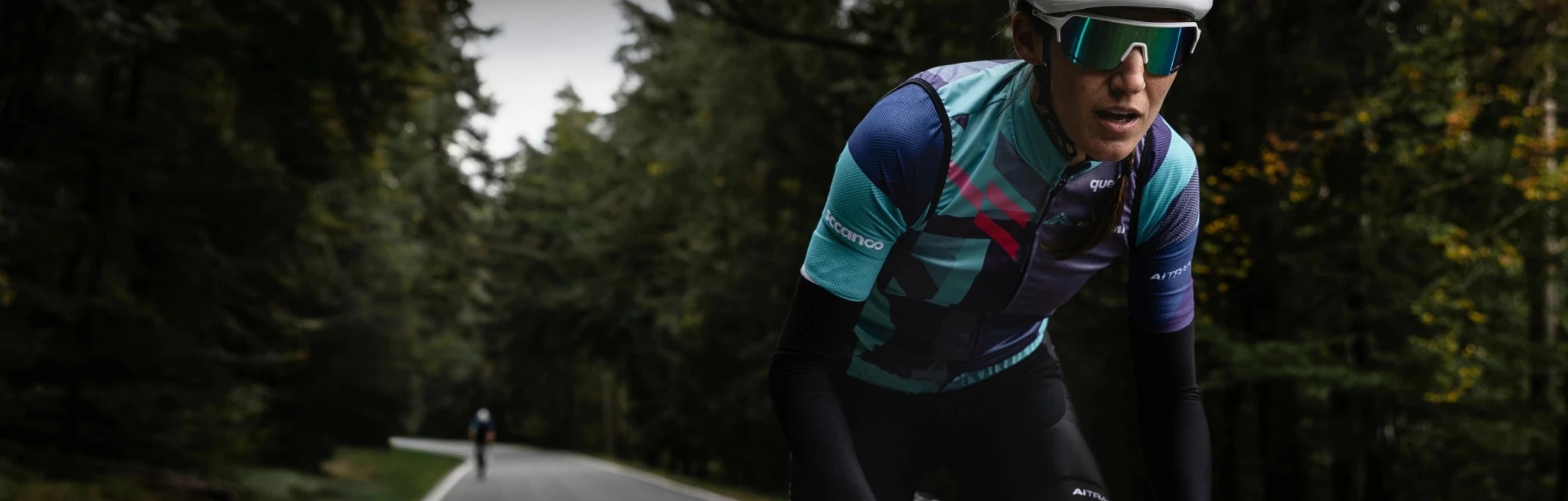 Female cyclist training intensely with INPEAK power meter for precise performance measurement on a forest road.