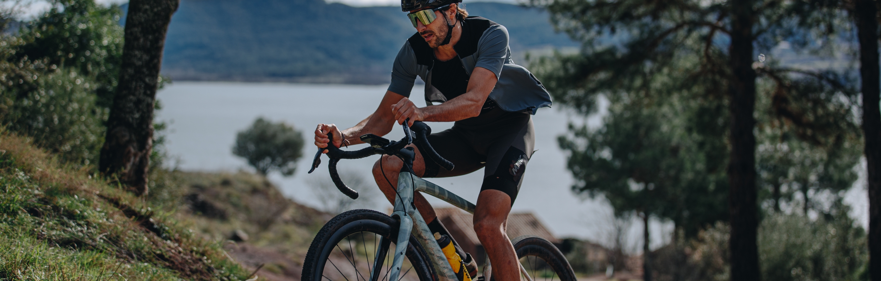 Radfahrer mit Mavic-Bekleidung fährt ein Gravel-Bike durch bergige Natur.