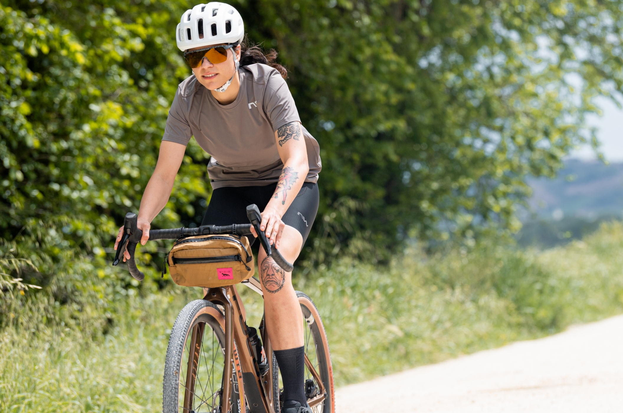 Northwave – Rennrad- & MTB-Schuhe, Brillen & Radbekleidung für Damen & Herren Gravelbikerin in lässigem Northwave-Outfit fährt entspannt durch grüne Landschaft.