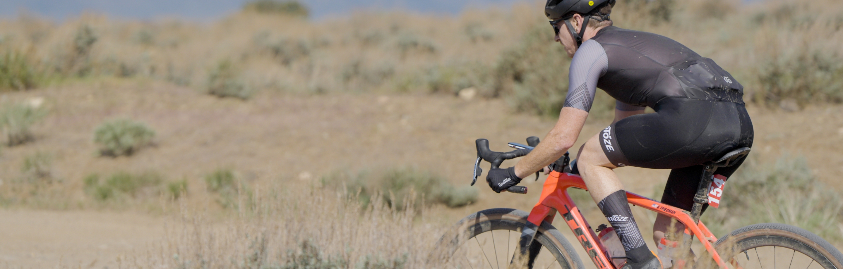 Dynamische Szene eines Radfahrers mit veloToze-Handschuhen und Socken auf einer Offroad-Strecke.