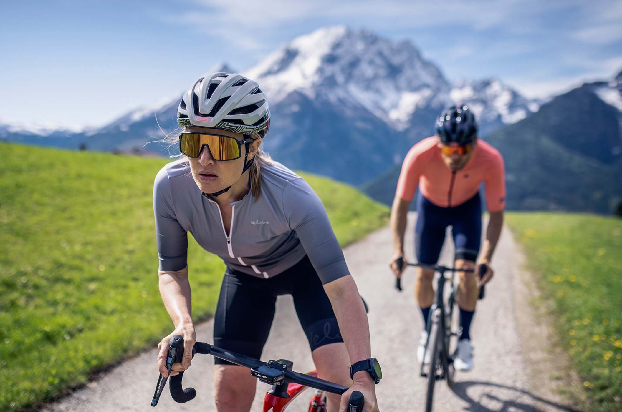 Frau und Mann auf Rennrädern fahren durch die Berge und tragen ABUS Fahrradhelme