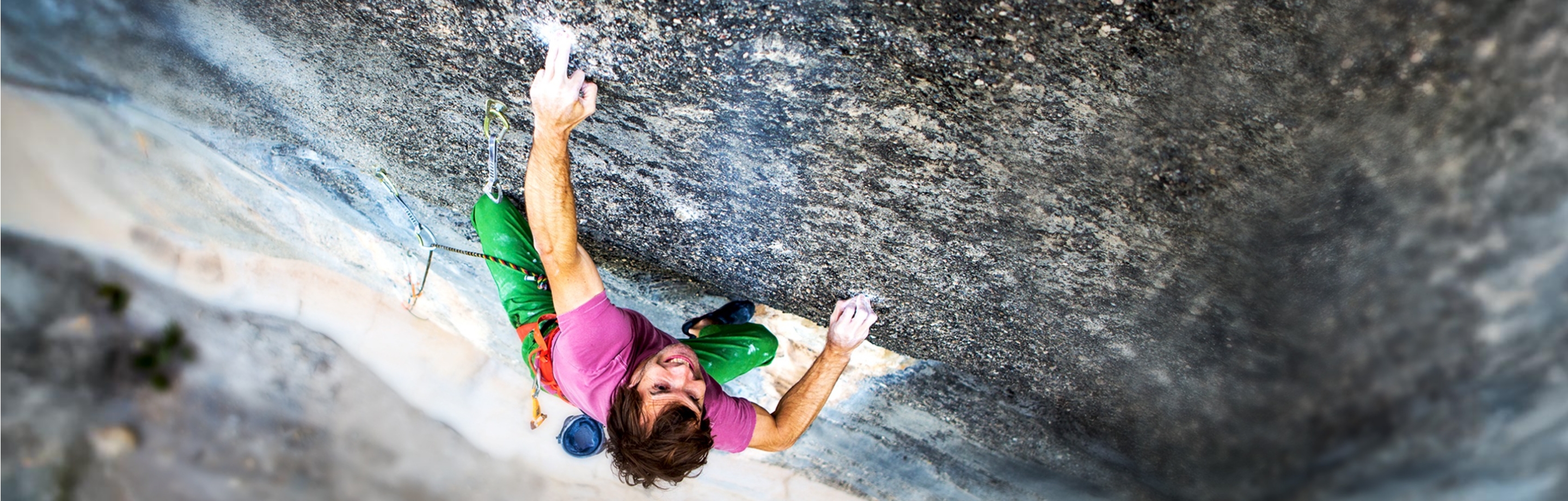 Persona que escala una pared de roca con equipamiento de escalada