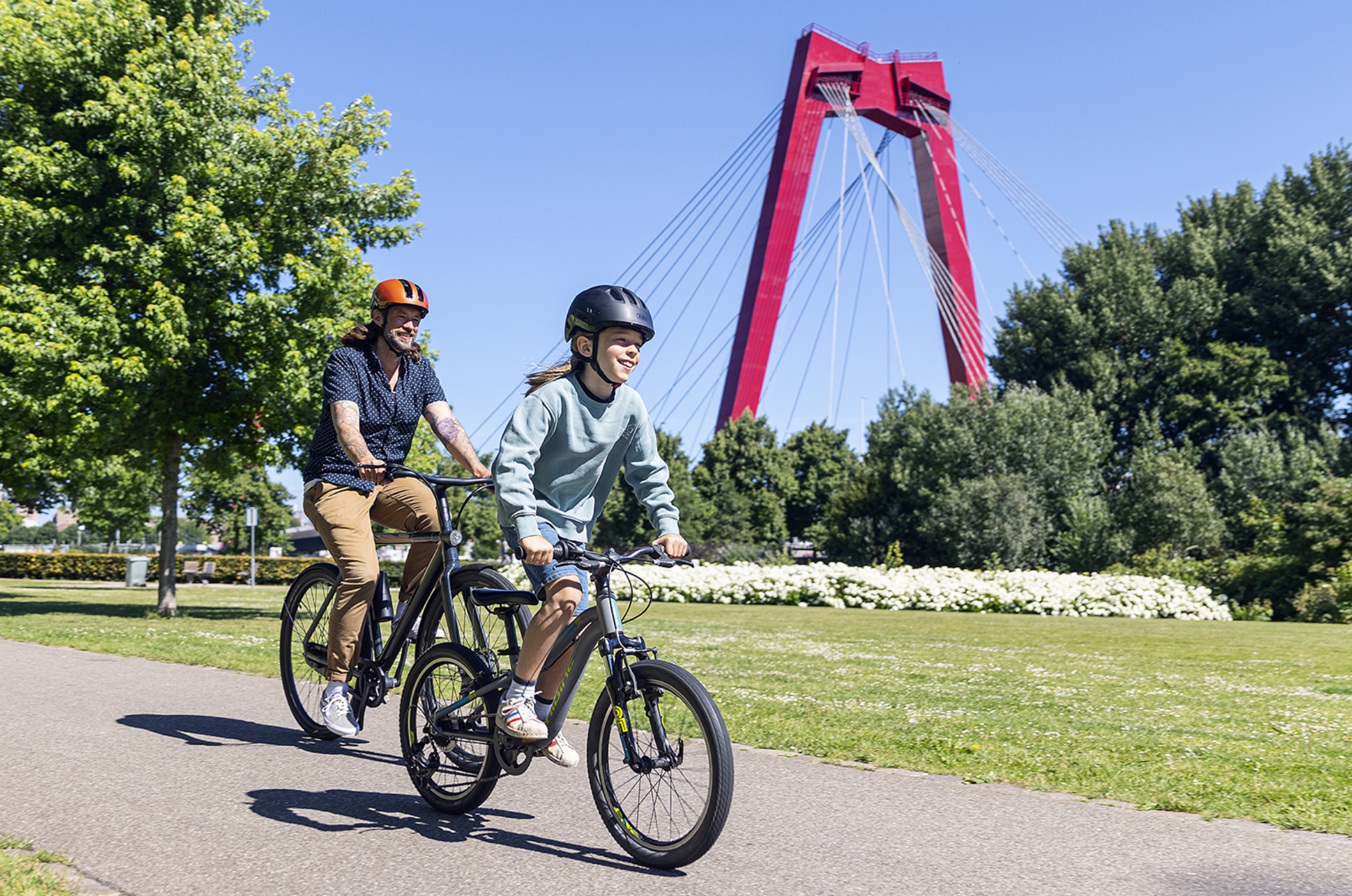 Vater und Sohn fahren durch die Stadt und tragen beide ABUS Fahrradhelme