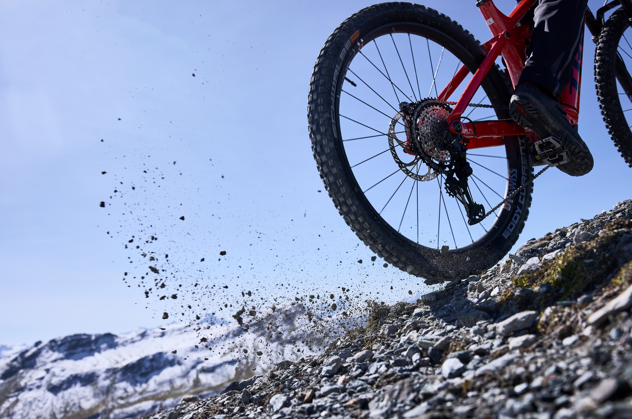 DT Swiss E-MTB-Laufräder – perfekt für raues Gelände Eine Person fährt mit DT Swiss Hybrid-Rädern einen Hügel hinauf und wirbelt dabei Kies auf.