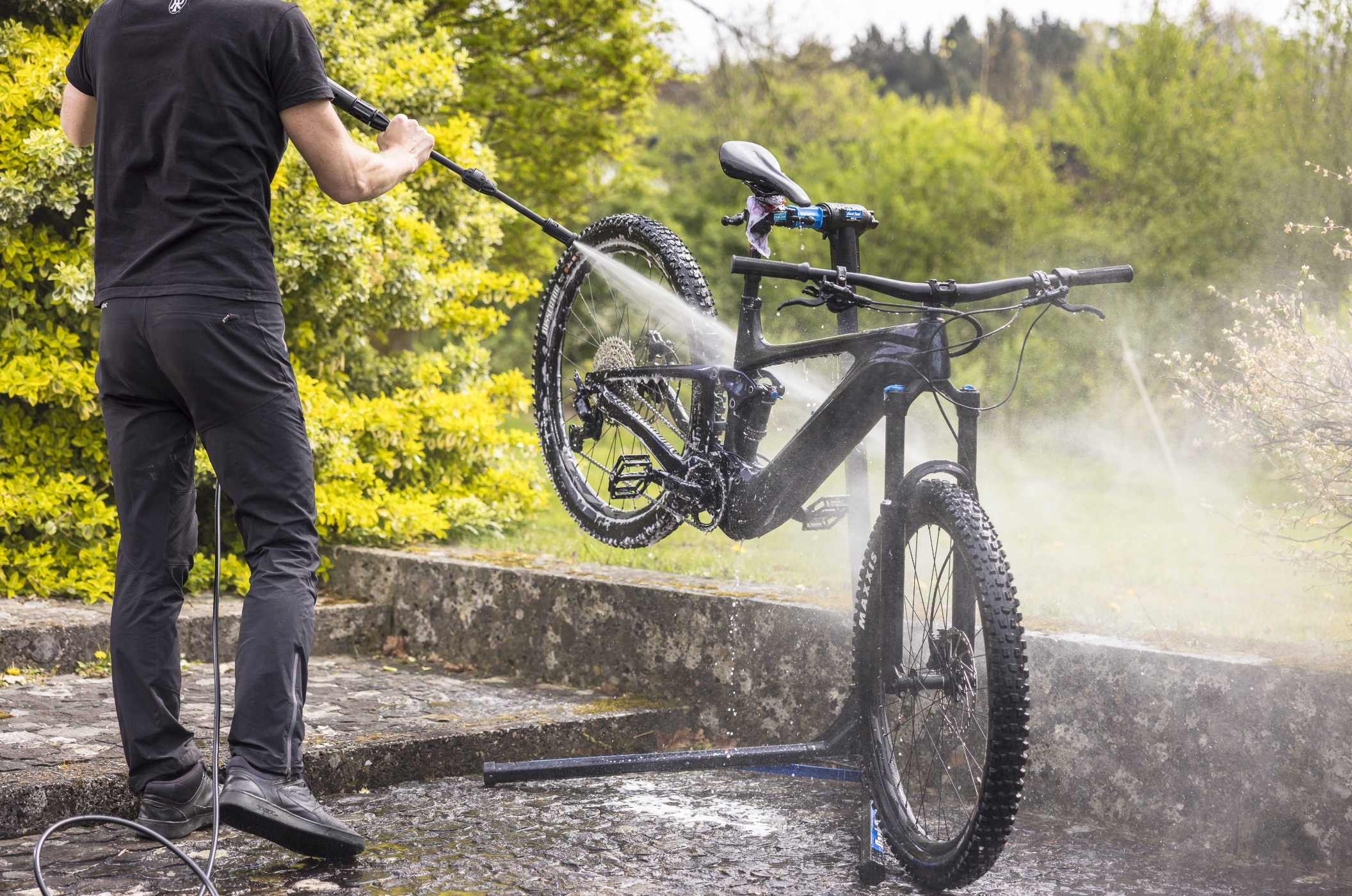 Dreckiges Fahrrad wird outdoor mit Hochdruckreiniger von Muc-Off gereinigt