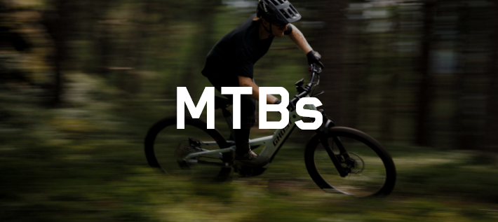Ciclista de montaña con una bici MTB Ghost en un sendero, imagen algo borrosa