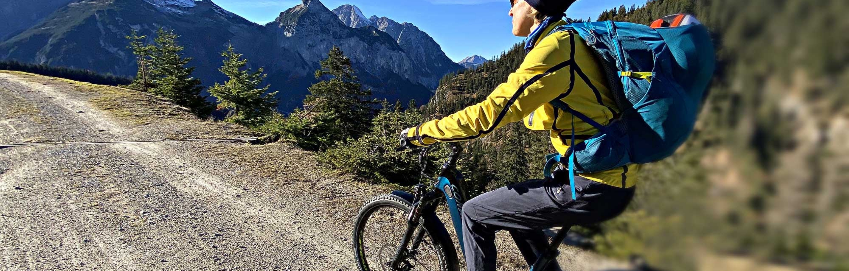 Mountainbiker met Tektro-remmen op een grindpad in de Alpen bij mooi weer.