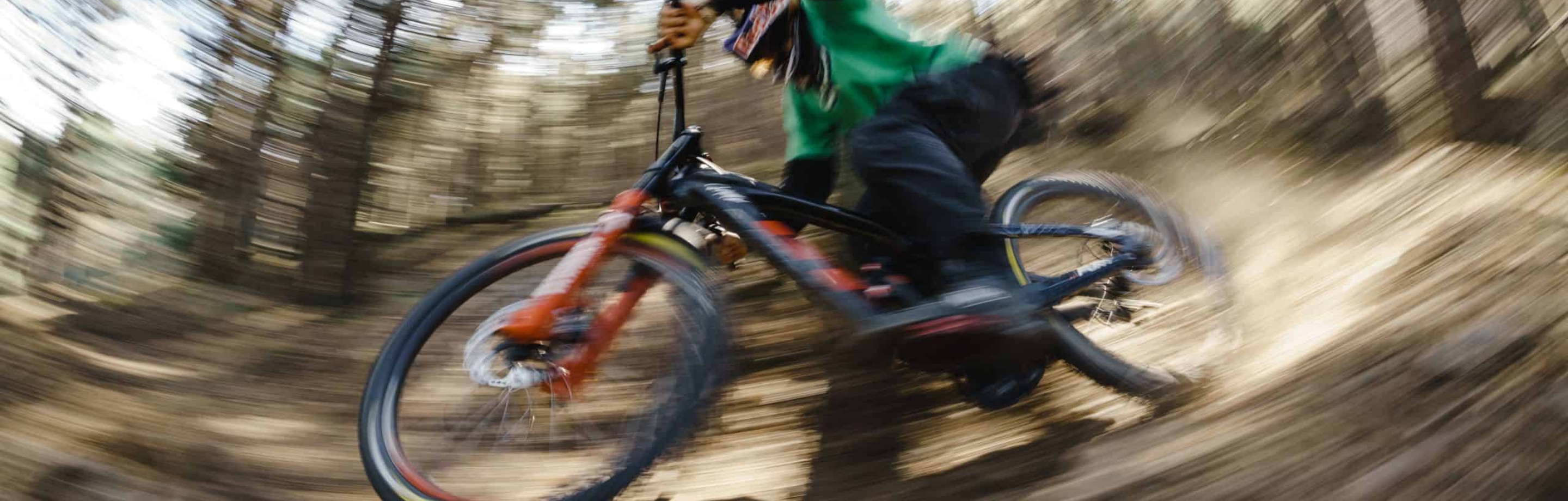 Dynamic forest ride on a mountain bike featuring Burgtec bike parts, emphasizing speed and action.