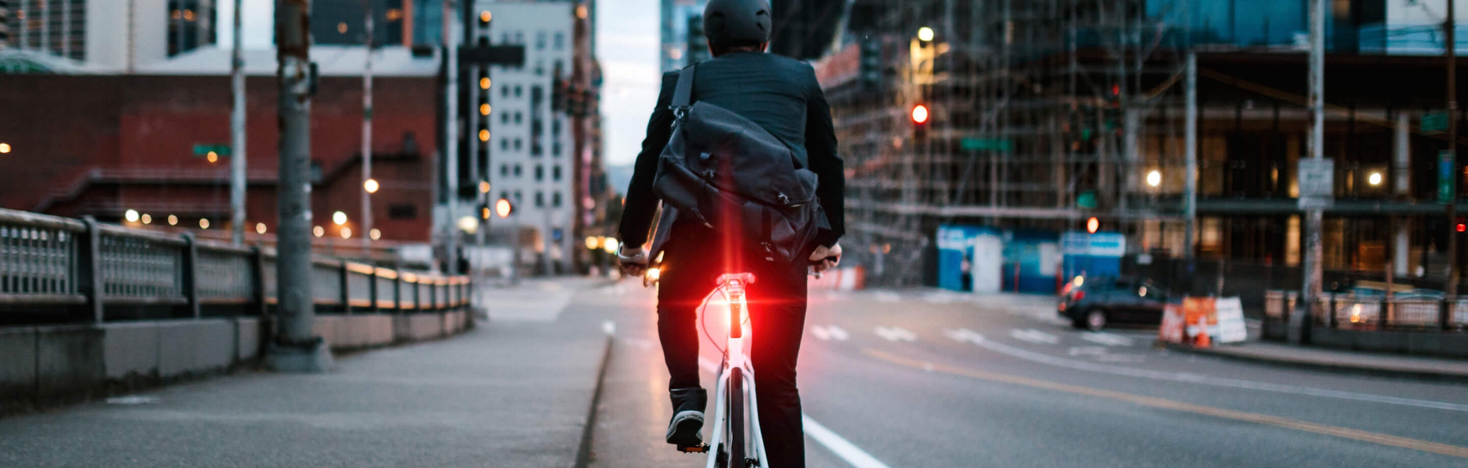 Hombre pedaleando por la ciudad con luz trasera Alps Alpine.