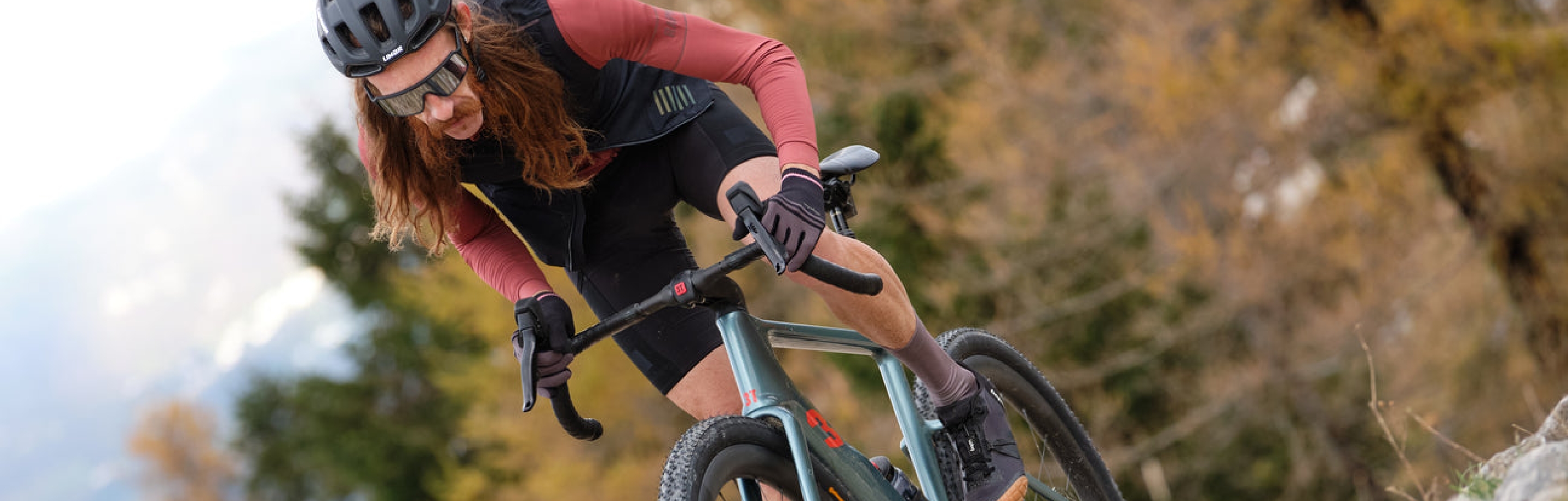 Hombre de pelo largo sobre una bicicleta en la montaña que tiene componentes de ciclismo de la marca 3T