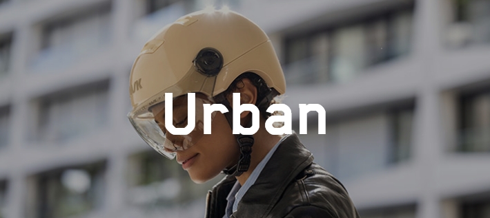 Junge Frau in städtischer Umgebung trägt einen cremefarbenen KASK Helm.