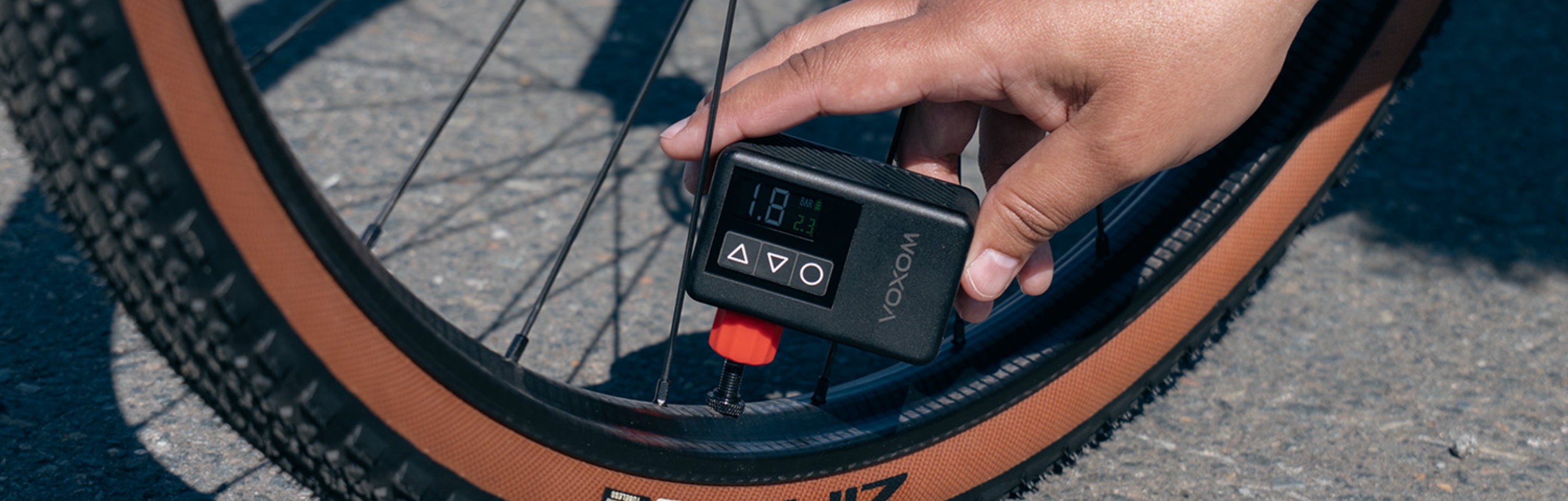 Osoba pompuje oponę w rowerze gravel za pomocą elektrycznej pompki rowerowej VOXOM.