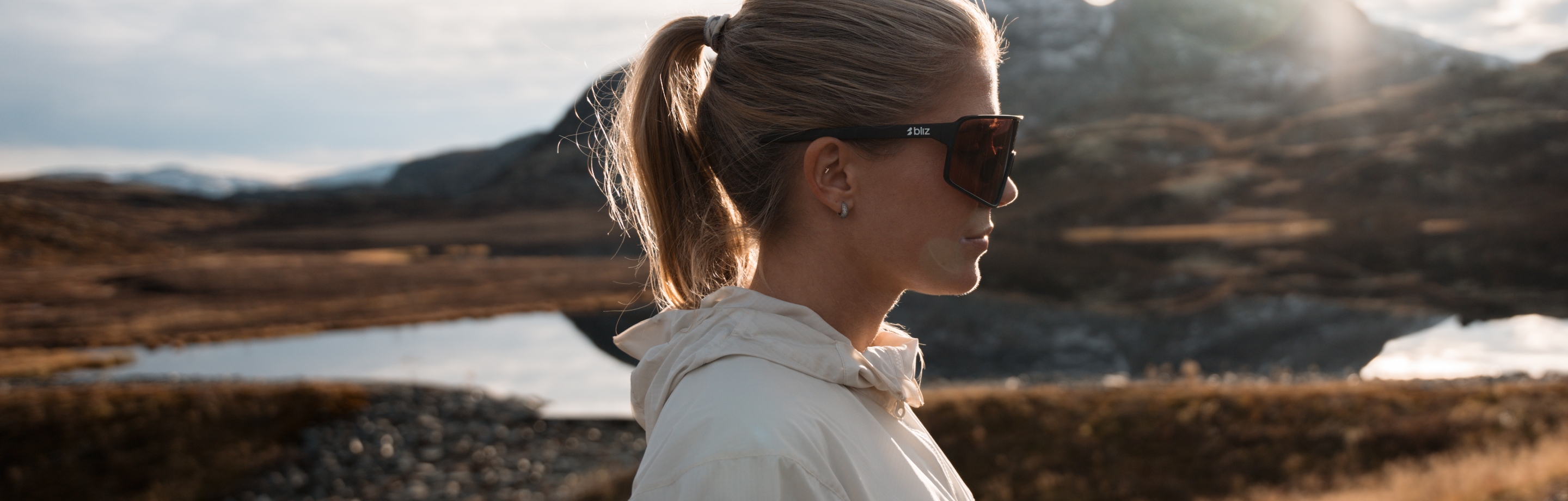 Functional Bliz sports sunglasses worn in a calm mountain setting under soft light.