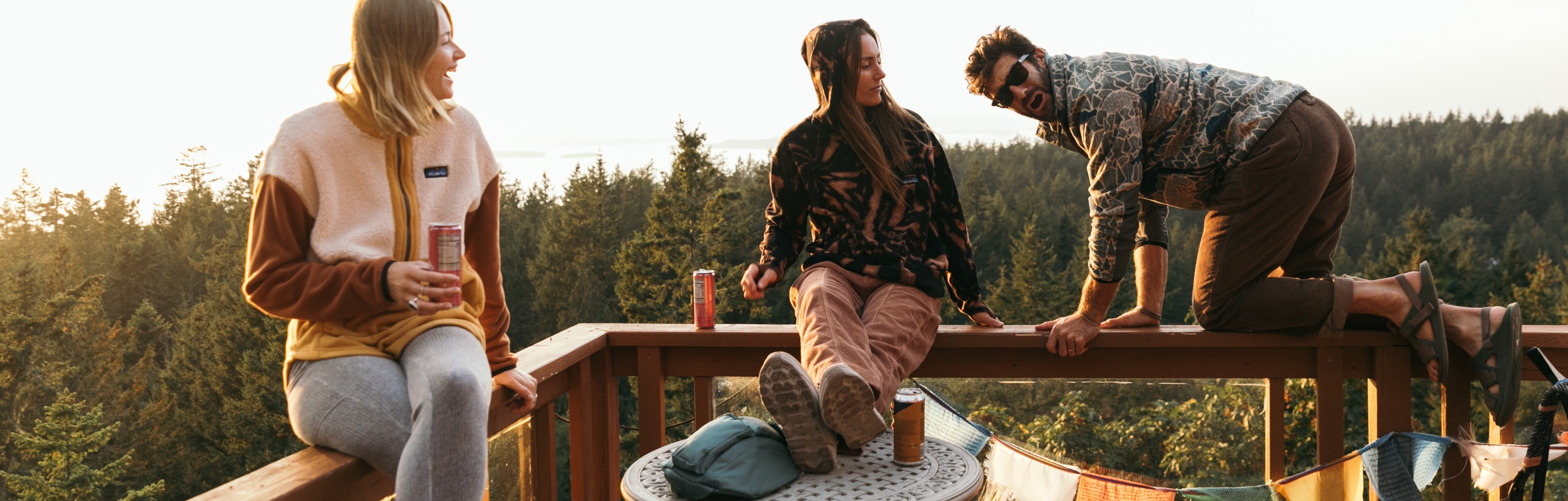 Two women and a man are chilling in the sun near the forest.