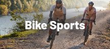Mann und Frau in VAUDE Fahrradbekleidung fahren mit Gravelbikes einen Fluss entlang