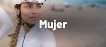 Mujer con ropa de ciclismo assos rosa suave y de fondo una playa poco nítida