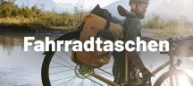 VAUDE – Fahrradtaschen Close-Up von einem Mann, der ein Fahrrad mit VAUDE Satteltaschen über einen Fluss trägt