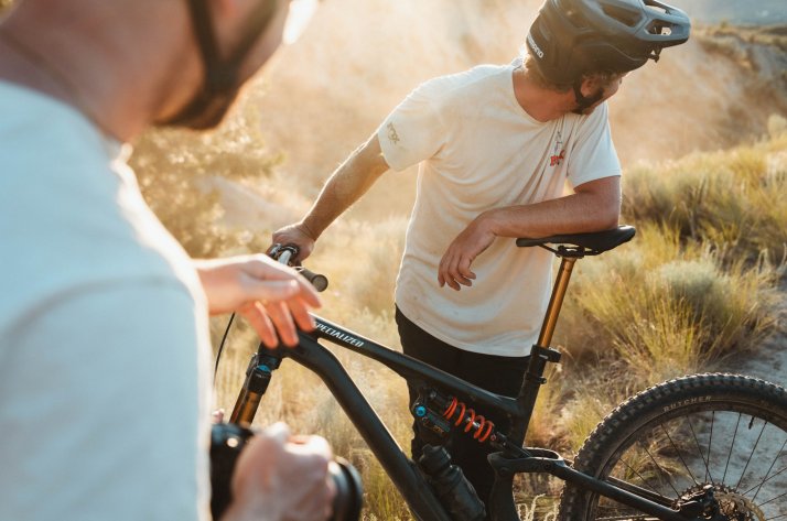 FOX Factory Transfer Neo Tiges de selle Deux cyclistes VTT se repèrent sur un sentier, tandis que l'un d'entre eux s'appuie sur sa potence FOX Transfer Neo.