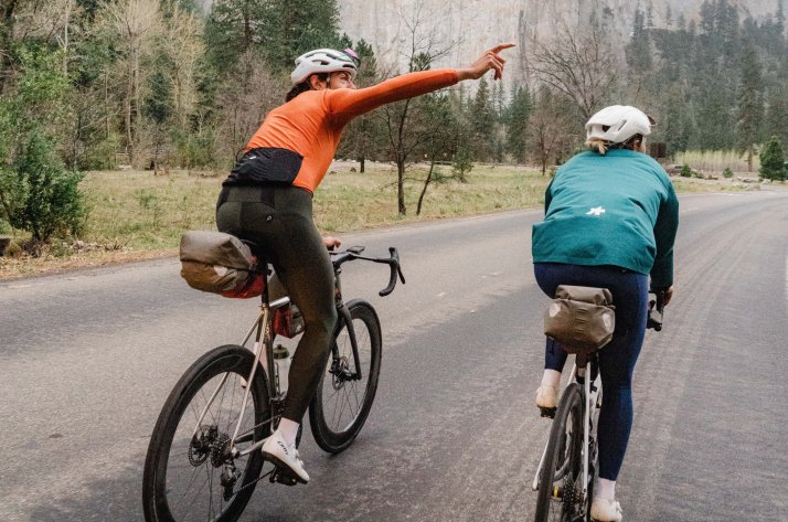 Dynamische Szene von Radfahrerinnen in ASSOS Outfits auf kurviger Bergstraße.