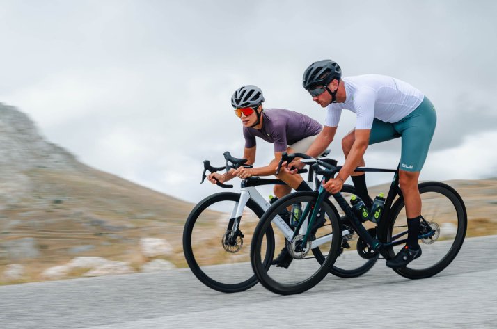 Two cyclists in Alé apparel riding on a mountain road.