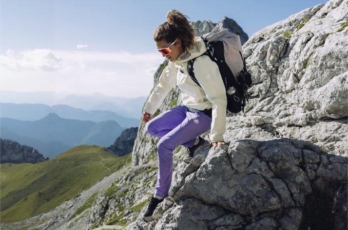 Een vrouw op bergtocht in alpien gebied, volledig gekleed in Mammut.