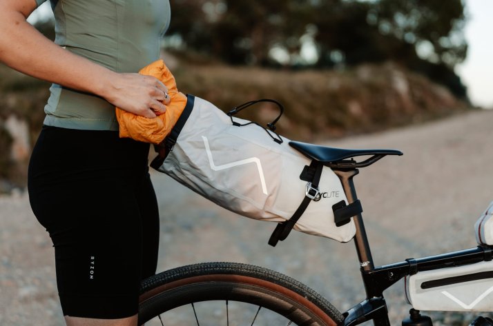 Ciclista che ripone nella borsa il sacco a pelo ripiegato