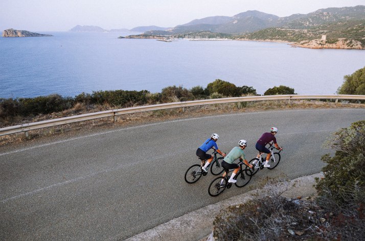 Three cyclists riding together in Santini cycling apparel on a winding coastal road