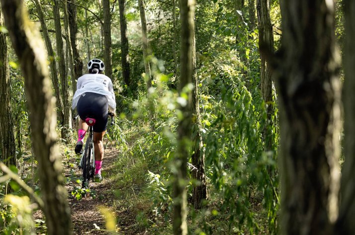 Radfahrerin auf Gravelbike mit ORTLIEB Mini-Satteltasche im Wald