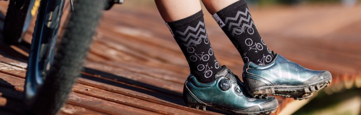 Sox Footwear – huippusuorituskykyiset sukat persoonallisella tyylillä Kuva kuvioiduista mustista Sox Footwear -sukista maastopyöräilijän jaloissa.