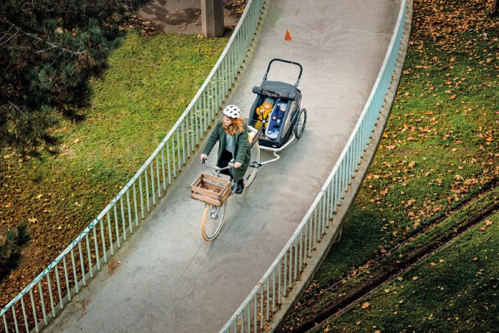 Frau mit Fahrradanhänger von Croozer fährt durch die Stadt Frau mit Fahrradanhänger von Croozer fährt durch die Stadt