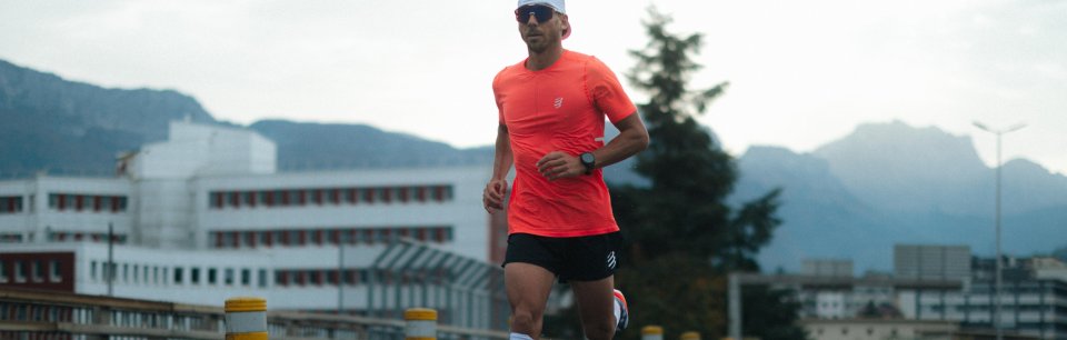 Läufer in leuchtend rotech urbane Umgebung mit Bergen im Hintergrund.