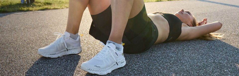 Une femme sportive se repose après une course, elle porte des chaussures running blanches Joe Nimble.