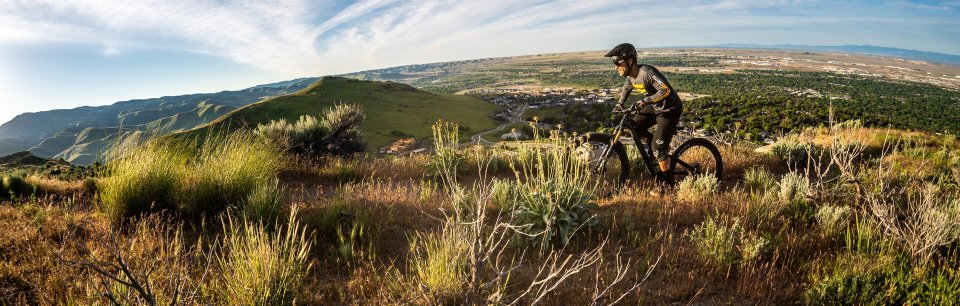 Ein Touren-Rider mit Deity Components am Bike fährt durch eine Steppenlandschaft.