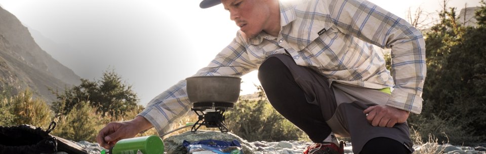 Horillo de gas en un camping de la marca Optimus y un chico haciendo el fuego