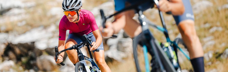 Mujer con ropa de ciclismo Alé subiendo un día soleado por una montaña