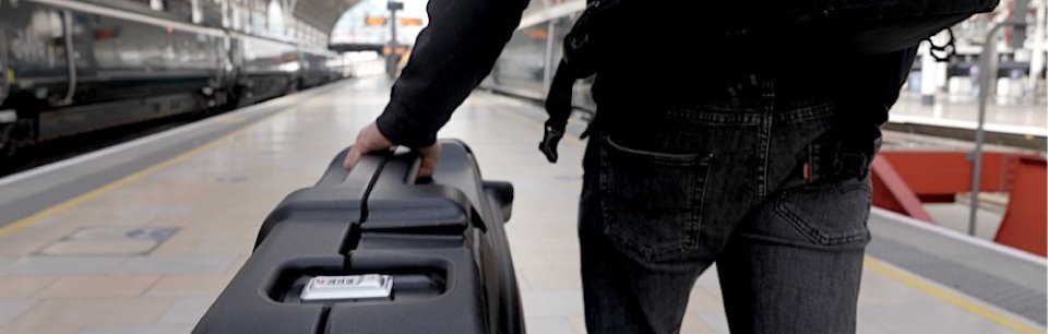 Een reiziger trekt de fietskoffer van ShokBox door een modern treinstation.