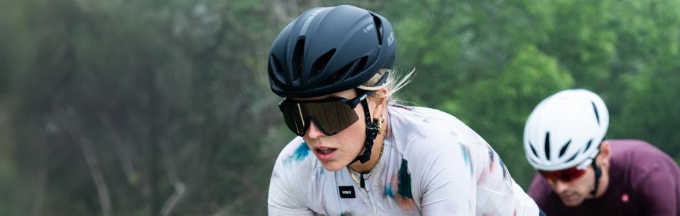 Close-up of a female cyclist wearing a matte black HJC helmet on a ride through green surroundings