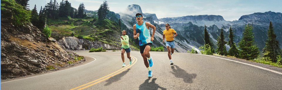 Groupe dynamique de coureurs avec des chaussures HOKA dans un décor montagneux incroyable.