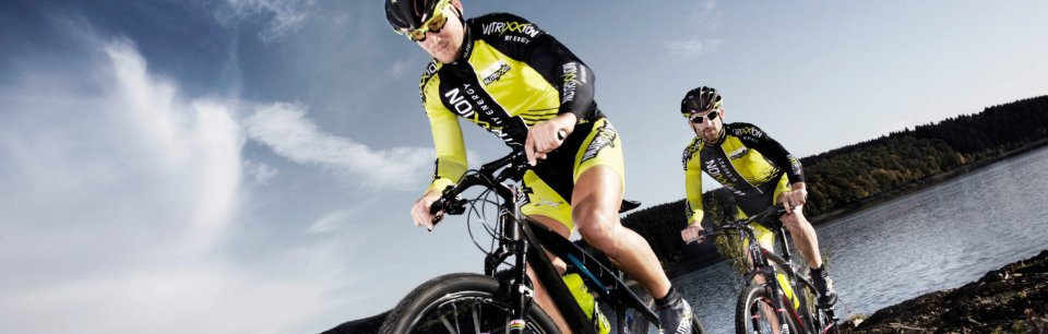 Due persone in bici che pedalano sulla riva di un lago