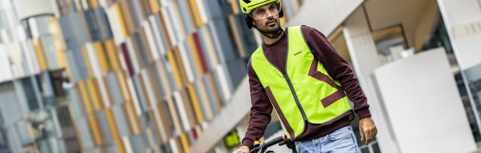 Hombre con una bicicleta y casco y chaleco reflectante de la marca WOWOW
