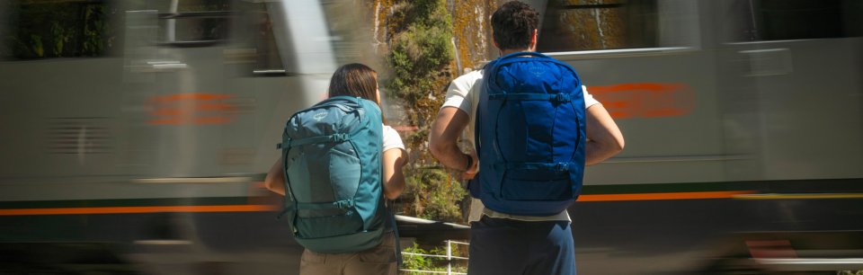 A couple with Osprey bags, waiting for a train