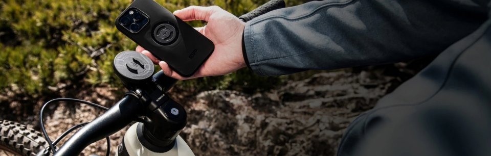 Persona que sujeta un teléfono móvil que está sujeto a un accesorio de la bicicleta