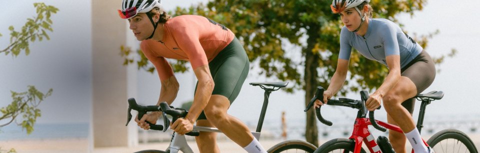 Twee wielrenners in Etxeondo-fietskleding rijden over een geplaveide weg.