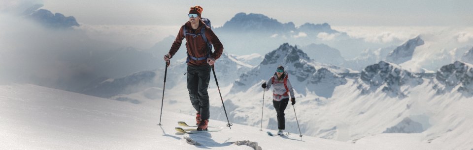Deux athlètes en tenue Karpos font du ski de randonnée dans les Alpes.