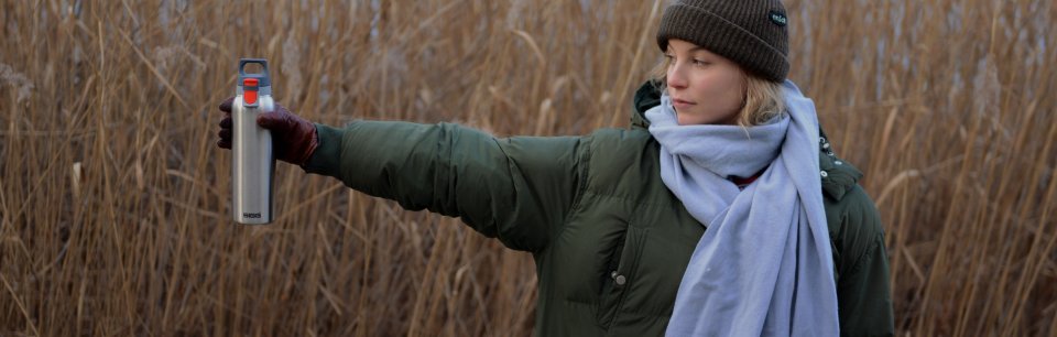 Mujer en el campo sosteniendo una botella SIGG.