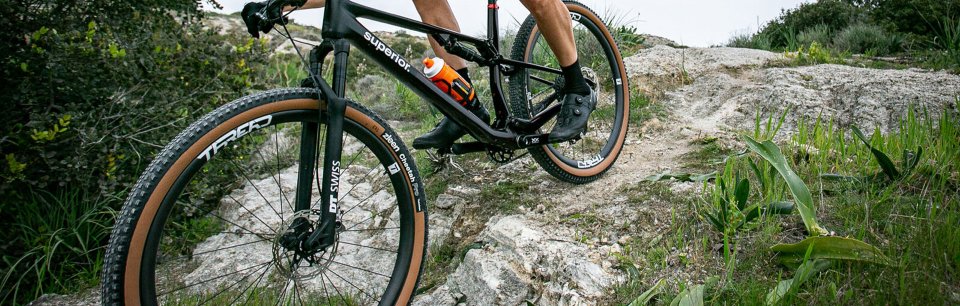 En mountainbiker på dæk fra Zleen kører over klippe