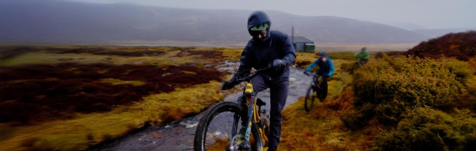 Zwei MTB-Fahrer*innen in Endura Funktionsbekleidung fahren entlang eine Bachlaufs.