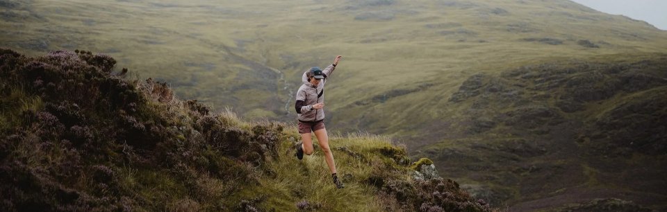 A runner in VÅGA gear, running on the crest of a mountain.